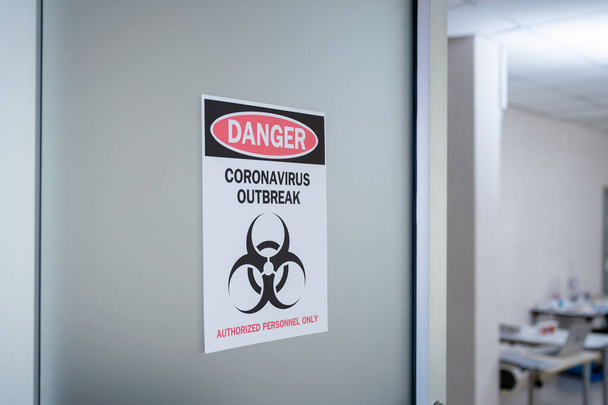 Aviso de alerta papel en la puerta del peligro brote de coronavirus con símbolo de peligro biológico y personal autorizado solamente - Foto, imagen