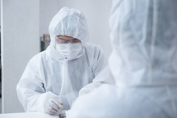 Команда химиков в защитном костюме изобретает и исследует антивирусный препарат Ковид-19, коронавирус в лаборатории - Фото, изображение