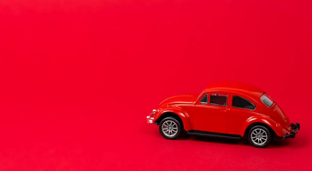 Vintage red car miniature model on a red background. Copy space. - Fotó, kép