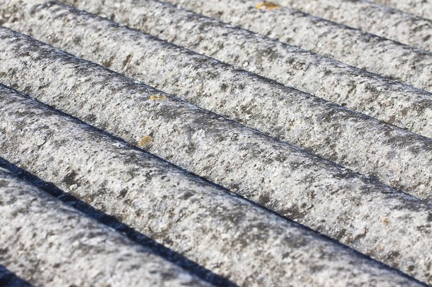 Detail eines in die Jahre gekommenen, gefährlichen Daches aus gewellten Asbestplatten - eines der gefährlichsten Materialien in der Bauindustrie, das als versteckter Killer bezeichnet wird. - Foto, Bild