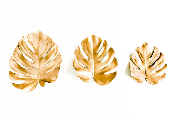 Gold tropical palm leaves Monstera on white background. Flat lay, top view minimal concept. - 写真・画像