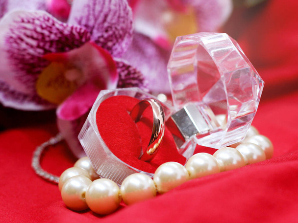 Golden wedding ring in the glass box on orchid background, love and happy - Foto, immagini