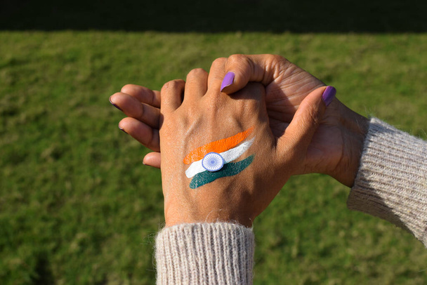 Femmina con bandiera indiana tri tatuaggio a colori sul dorso della mano in occasione della giornata della repubblica indiana con fiori bianchi che rappresentano la pace. - Foto, immagini