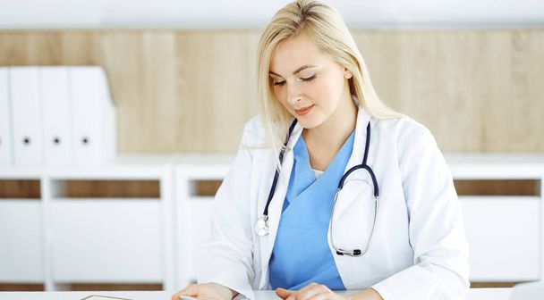 Woman-doctor standing in hospital or clinic and using tablet pc. Data and best service in medicine and healthcare - Photo, Image