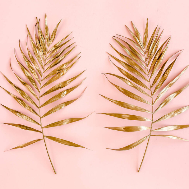 Gold tropical palm leaves on pink background. Flat lay, top view minimal concept. - Photo, image