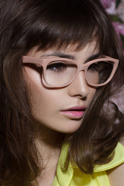 Gros plan portrait de beauté d'une fille avec des lunettes de vue nues roses, peau et maquillage parfaits, coiffure courte. Vue verticale. - Photo, image