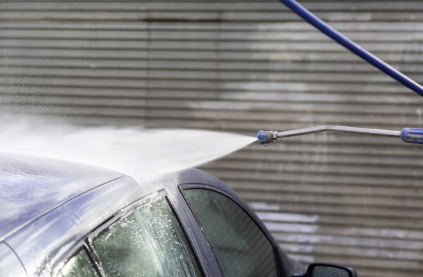 Washing car with hose and soap, mechanical workshop, vehicle maintenance - Photo, image