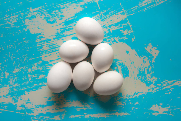 Chicken eggs lie on a vintage blue background with scratches. - Foto, afbeelding