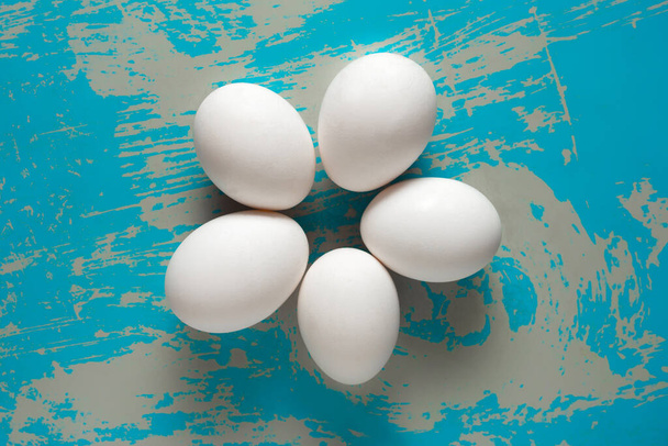 Huevos de pollo yacen sobre un fondo azul vintage con arañazos. - Foto, imagen