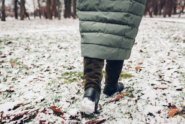 Detailní záběr ženských zimních bot. Žena kráčející ve zasněženém parku v dlouhém teplém kabátě a vysokých zelených semiš boty - Fotografie, Obrázek