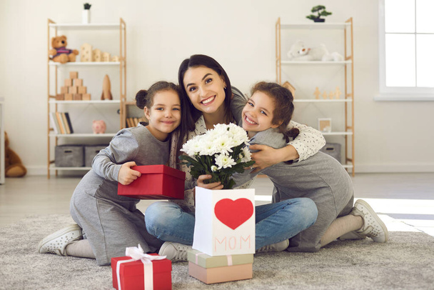 Portrait of happy mom with presents and flowers embracing her children on Mothers Day - Foto, Bild