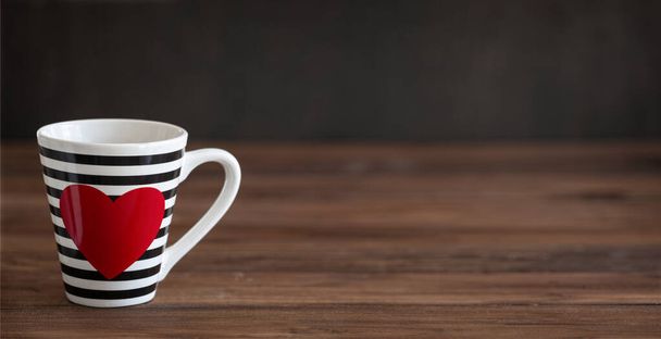Stripy black and white cup with red heart on wooden background. Valentine's Day Cup. Love Concept - Photo, Image
