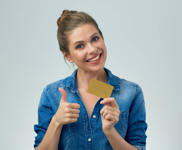 smiling woman in blue shirt holding credit card and showing thumb up. isolated female portrait. - Photo, Image