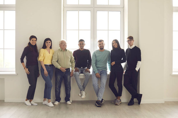 Team of cheerful diverse people standing by the window, smiling and looking at camera - Fotoğraf, Görsel