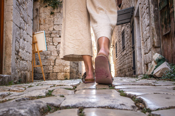 Detalhe tiro de pernas femininas vestindo sandálias de viagem confortáveis andando em pedras de paralelepípedos medievais velhos rua dring passeio pela cidade. Viagens, turismo e conceito de aventura - Foto, Imagem