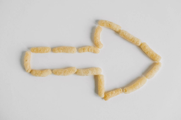 Corn sticks scattered in the shape of an pointer on a white background. Top view. Place for your text. - Photo, Image