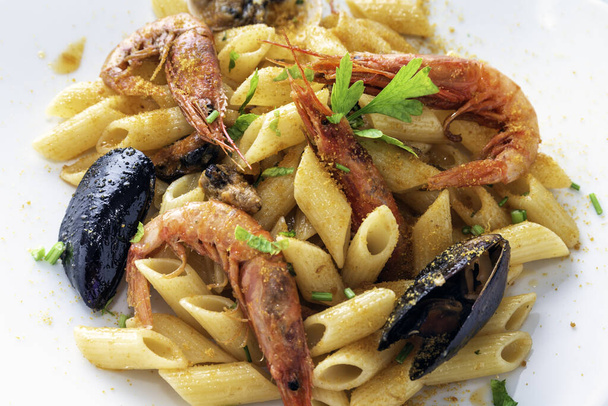 Jídlo z lahodného penne allo scoglio, typický recept na těstoviny s mušlí, krevetami, škeblemi a bottargou, italská kuchyně  - Fotografie, Obrázek