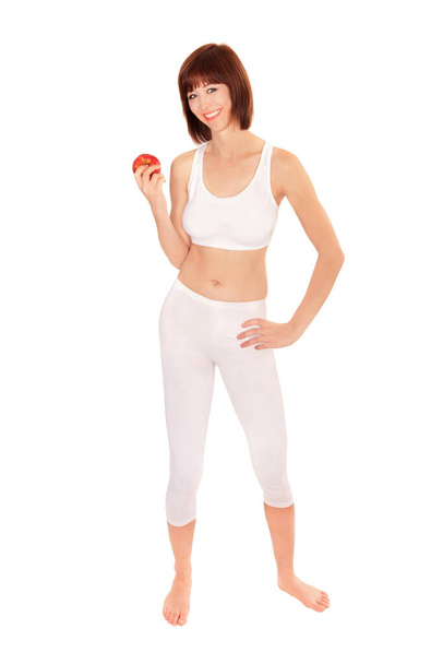 Plný portrét atletické mladé ženy držící jablko, izolované na bílém pozadí studia - Fotografie, Obrázek