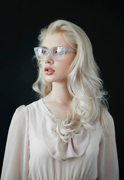 Gros plan portrait avant d'une belle femme blonde portant des lunettes, regardant un côté, sur fond noir. - Photo, image