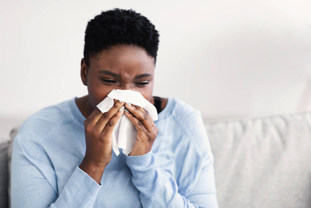 Sick black woman sneezing, holding tissue paper - Фото, изображение