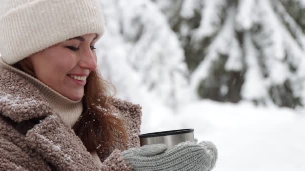 szabadság és boldogság koncepció - közelkép egy boldog nőről, aki teát iszik a téli erdőben - Felvétel, videó