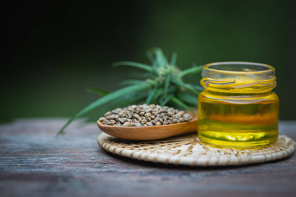 Glass bottles containing  hemp oil and hemp seeds in a wooden spoon,  drugs extracted CBD Cannabis Oil  of researchers or medical team. Herbal alternative medicine. - Photo, Image