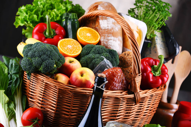 Panier en osier avec divers produits d'épicerie, y compris des légumes et fruits frais - Photo, image