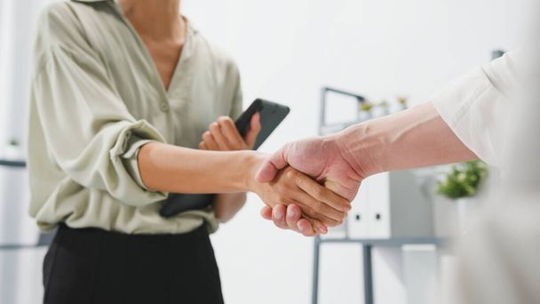 Multiracial group of young creative people in smart casual wear discussing business shaking hands together and smiling while standing in modern office. Partner cooperation, coworker teamwork concept. - Photo, Image