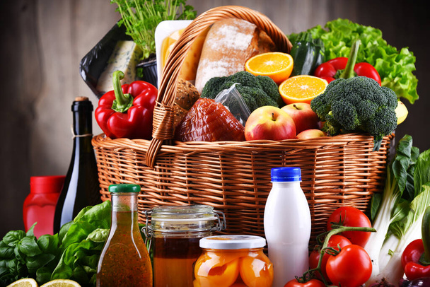 Cesta de mimbre con una variedad de productos de alimentación, incluyendo verduras y frutas frescas - Foto, Imagen
