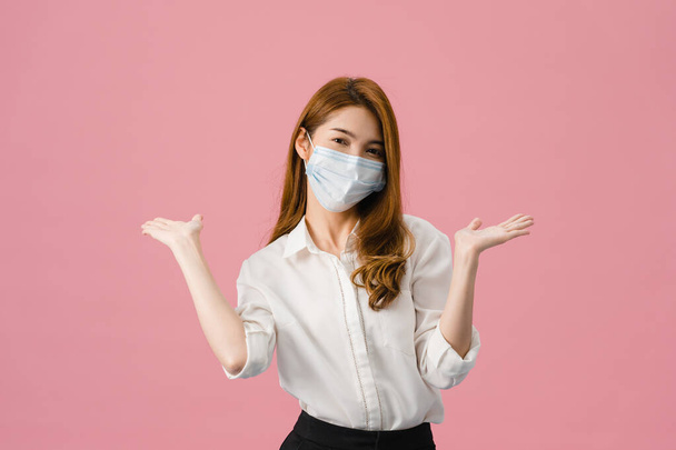 Young Asia girl wearing medical face mask showing peace sign, encourage with dressed in casual cloth and looking at camera isolated on pink background. Social distancing, quarantine for corona virus. - Photo, Image
