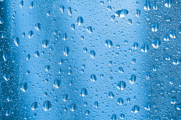Дощові краплі на склі в дощову погоду. Блискуча, блискуча поверхня води на склі. Вода падає у вигляді кульок або сфер. Абстрактний орнамент з водою
 - Фото, зображення