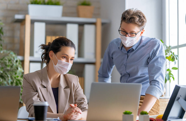 Businessman and businesswoman with medical mask working in office. Covid-19 time. - 写真・画像