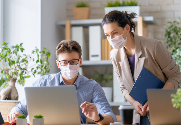 Businessman and businesswoman with medical mask working in office. Covid-19 time. - Foto, Bild