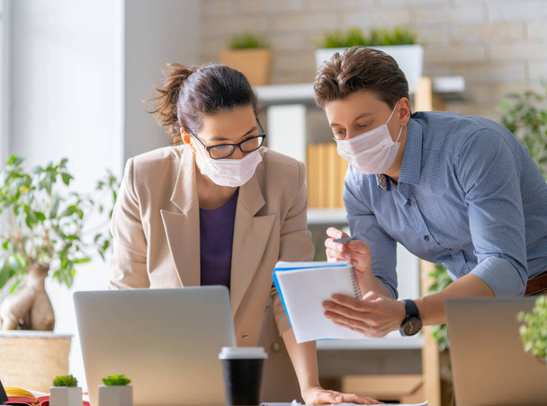 Businessman and businesswoman with medical mask working in office. Covid-19 time. - Foto, Imagem