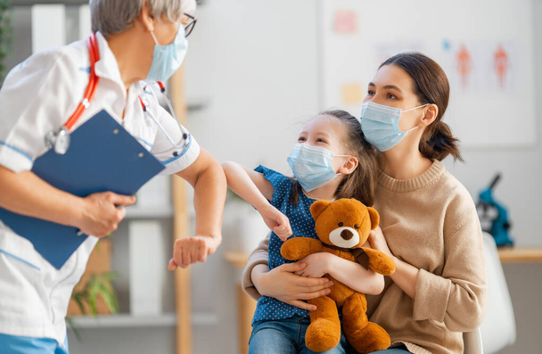 Doctor and child wearing facemasks during coronavirus and flu outbreak. Virus protection. COVID-2019. Taking on masks. - 写真・画像