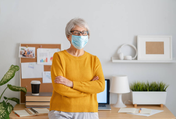 Woman in facemask working in home office. - Fotoğraf, Görsel