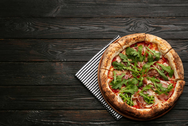 Tasty pizza with meat and arugula on black wooden table, top view. Space for text - Foto, immagini
