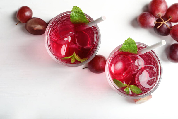 Вкусная виноградная содовая вода и ягоды на белом деревянном столе, плоский уголок. Освежающий напиток - Фото, изображение