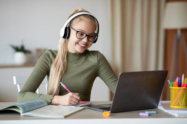 Positive school girl studying from home in front of laptop - Foto, immagini