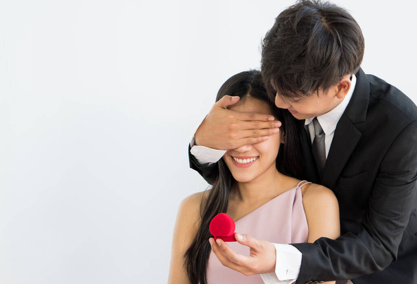 junger asiatischer Mann überrascht Freundin und macht ihr einen Heiratsantrag mit Ring auf weißem Hintergrund. Paar zusammen und valentines Konzept - Foto, Bild