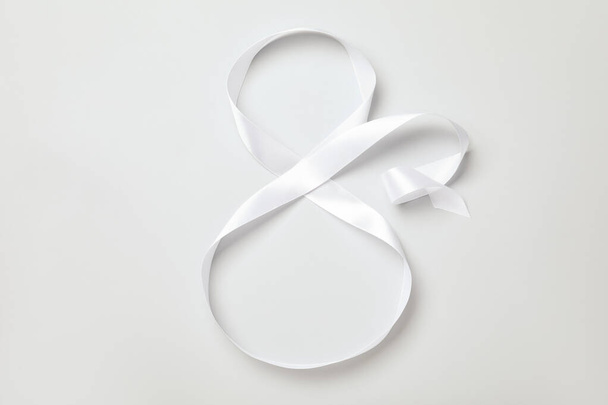 Number 8 made of white ribbon on light grey background, top view. International Women's day - Foto, Imagen