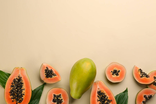 Fresh ripe papaya fruits with green leaves on beige background, flat lay. Space for text - Zdjęcie, obraz
