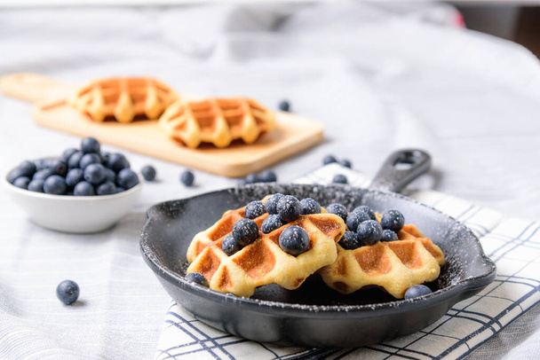 Homemade Waffles blueberries and icing on a dish that looks like a pan. - Foto, Bild