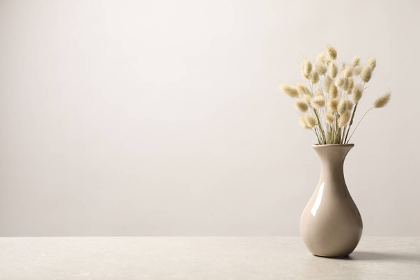 Dried flowers in vase on table against light background. Space for text - Valokuva, kuva