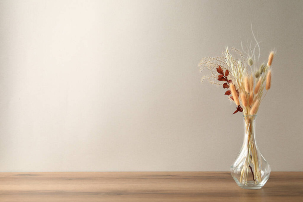 Dried flowers in vase on table against light background. Space for text - Foto, Imagen