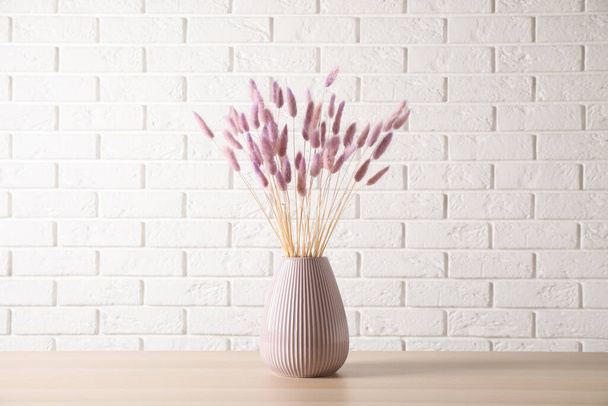 Dried flowers in vase on table against white brick wall - Photo, Image