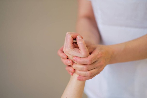 Rannehieronta. Hierontaterapeutti painostaa herkkää kohtaa naisten kädessä. Fysioterapeutti hieroo potilaitaan käsi lääketieteellisessä toimistossa - Valokuva, kuva