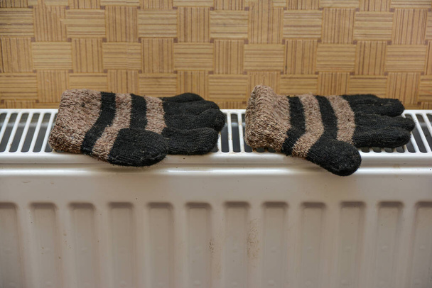 Bébé moufles en laine d'hiver sèchent sur le chauffage après s'être mouillé. - Photo, image