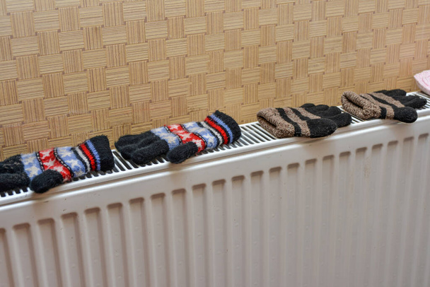 Children's winter woolen mittens are dried on the heater after playing in the snow. - Photo, Image