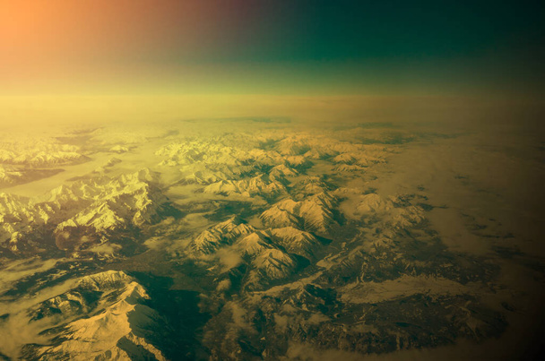 Δραματική εννοιολογική εικόνα της άποψης των βουνών σε σχέση με μια κατάσταση έκτακτης ανάγκης που συνδέεται με την παγκόσμια μετάδοση και τη δηλητηρίαση της ατμόσφαιρας. Πράσινα και κίτρινα βασικά χρώματα. - Φωτογραφία, εικόνα